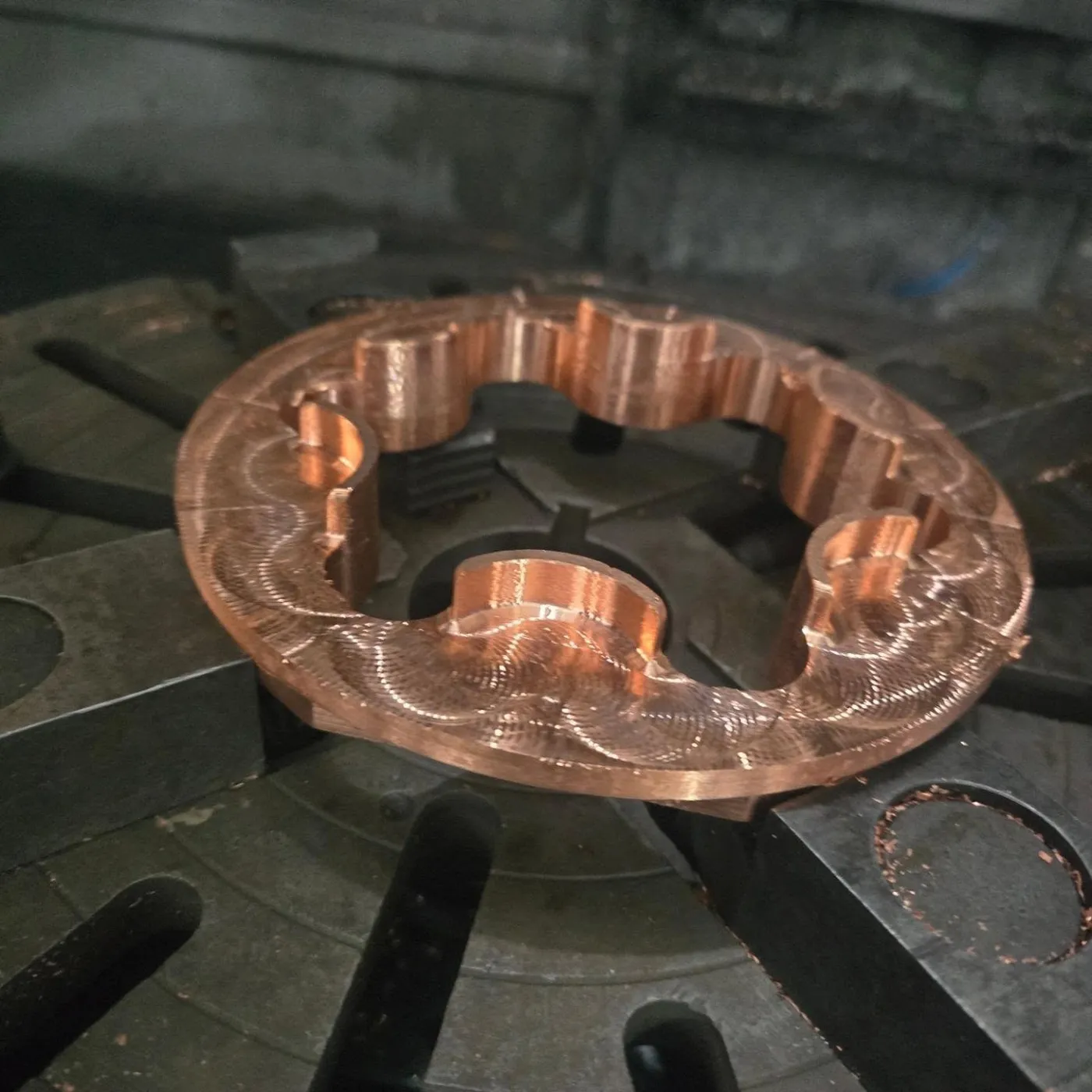 Peça em cobre usinada, ainda presa na mesa da máquina