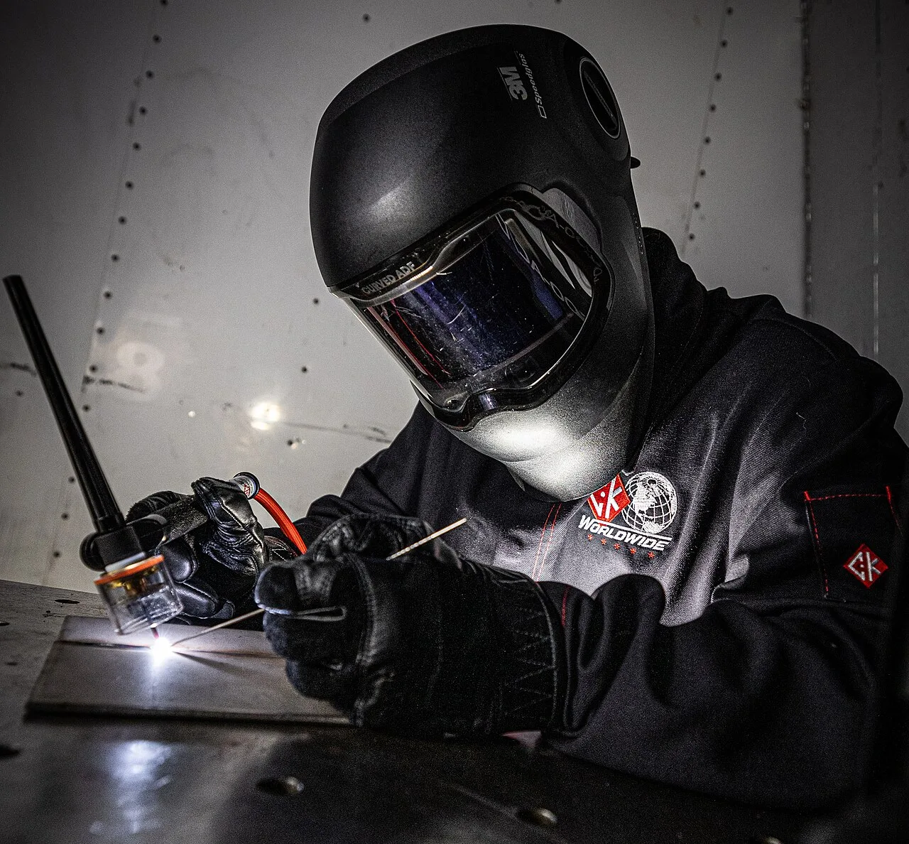 Soldador de capacete fazendo solda TIG (imagem ilustrativa)